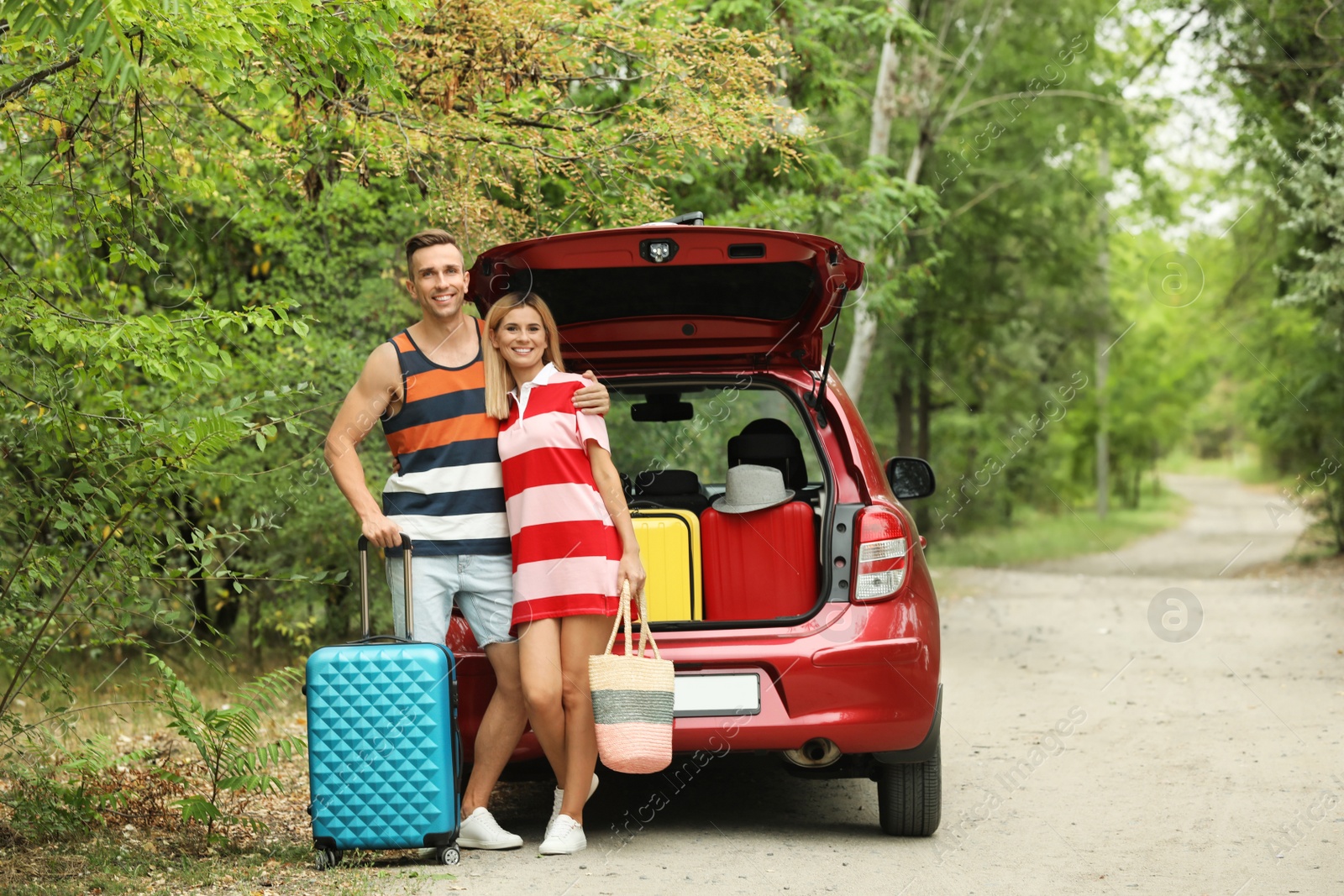 Photo of Happy couple near car trunk with suitcases outdoors. Space for text