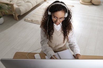 Photo of African American woman with headphones studying at home, above view. Distance learning