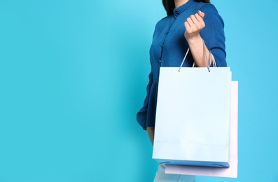 Woman with blank paper bags against color background, closeup. Space for text