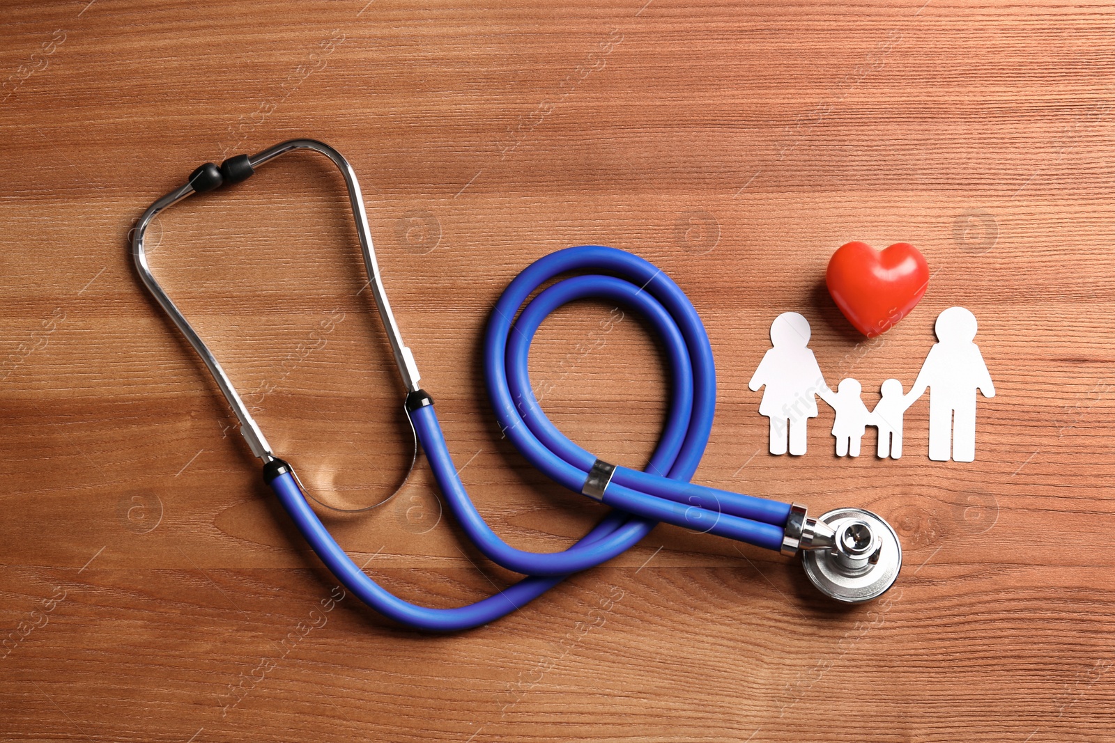 Photo of Flat lay composition with heart, stethoscope and paper silhouette of family on wooden background. Life insurance concept