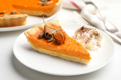 Slice of delicious homemade pumpkin pie on white wooden table, closeup