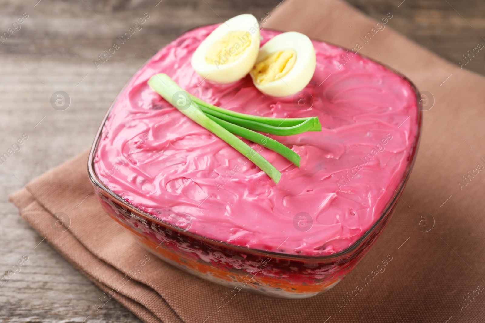 Photo of Herring under fur coat salad on wooden table, closeup. Traditional Russian dish