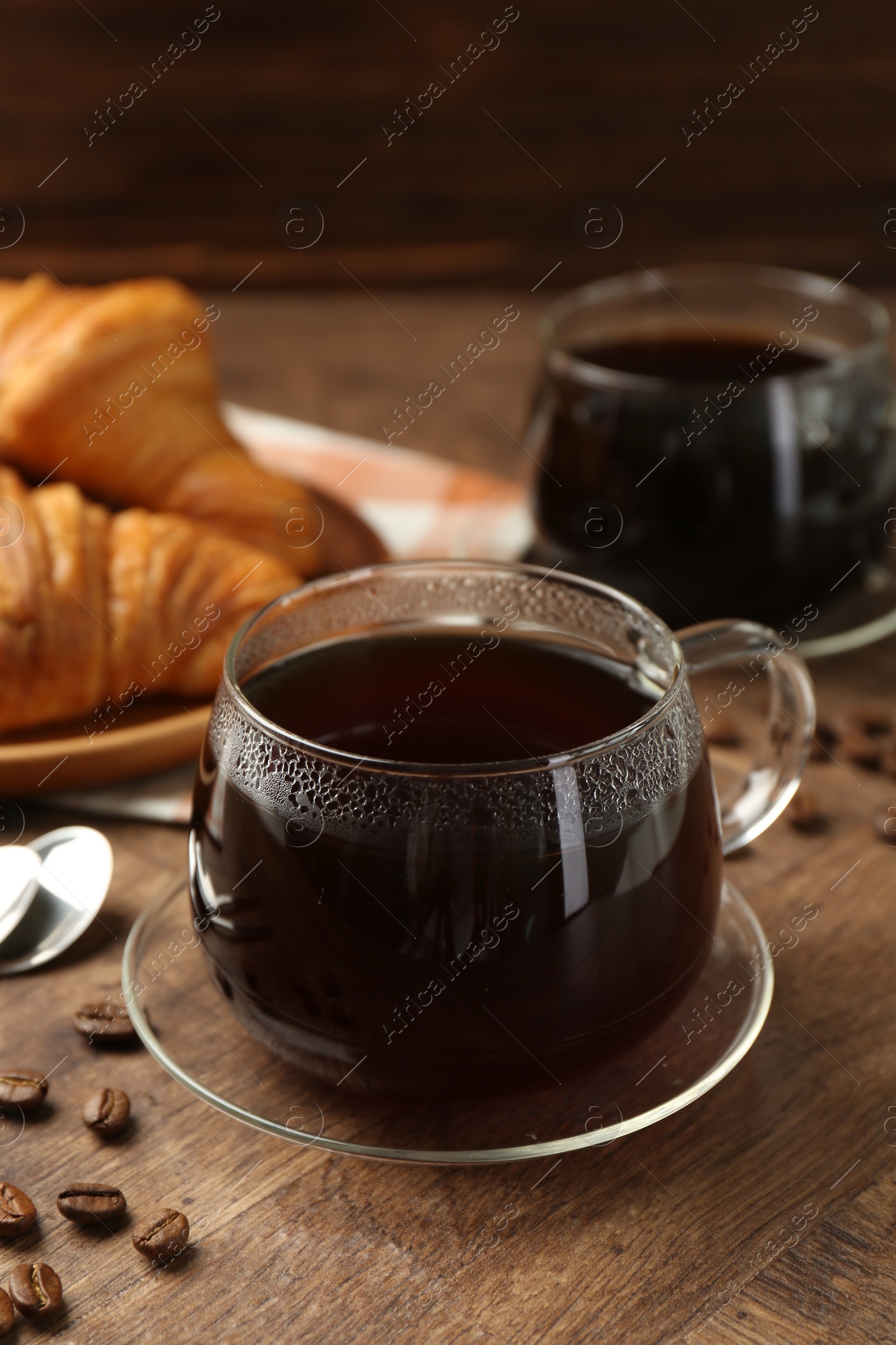 Photo of Hot coffee in glass cup and beans on wooden table, closeup