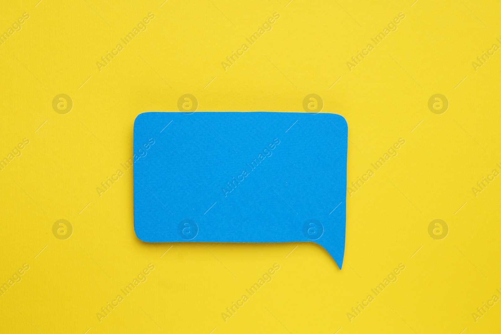 Photo of Paper speech bubble on yellow background, top view. Space for text