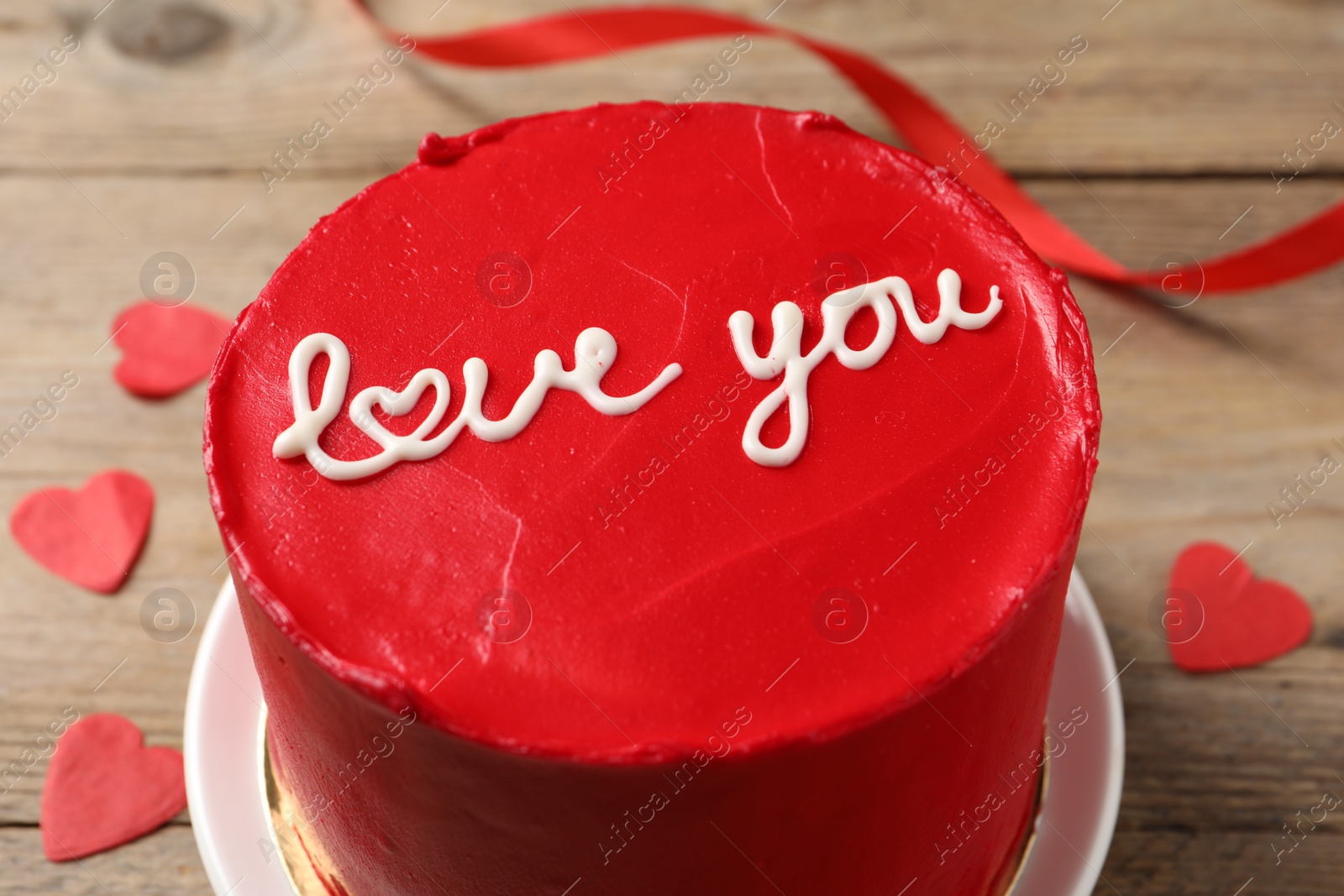 Photo of Bento cake with text Love You and paper hearts on wooden table, closeup. St. Valentine's day surprise