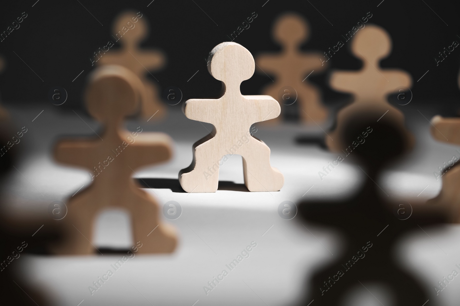 Photo of Recruitment and hiring concept. Human wooden figure in beam of light among others on table