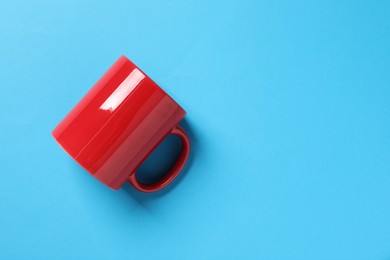 Photo of One red ceramic mug on light blue background, top view. Space for text