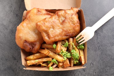 Photo of Tasty fish, chips and peas in paper box on grey table, top view