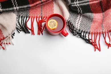 Flat lay composition with tea and warm plaid on white background, space for text