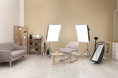 Photo of Interior of modern photo studio with rocking chair, table and professional equipment