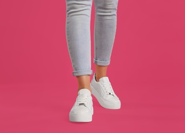 Woman wearing shoes on pink background, closeup