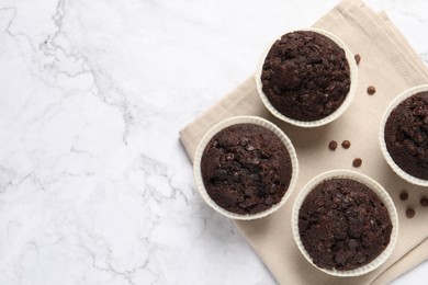 Photo of Tasty chocolate muffins on white marble table, top view. Space for text