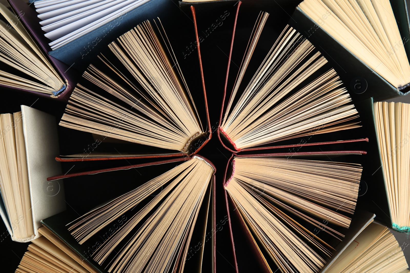 Photo of Many different hardcover books on dark background, top view