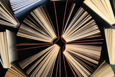 Photo of Many different hardcover books on dark background, top view