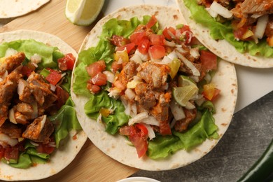 Photo of Delicious tacos with vegetables and meat on grey textured table, flat lay