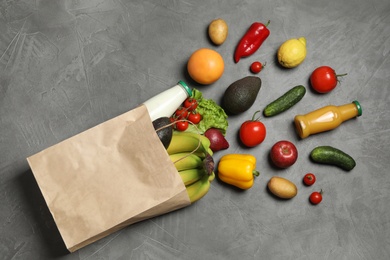 Photo of Paper bag with groceries on grey background, flat lay