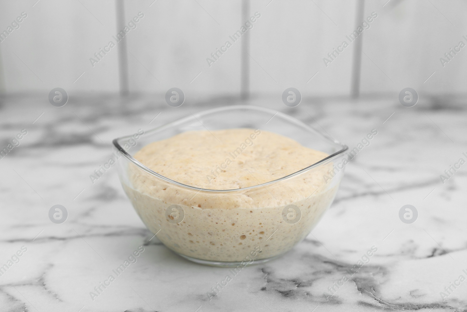 Photo of Leaven in glass bowl on white marble table