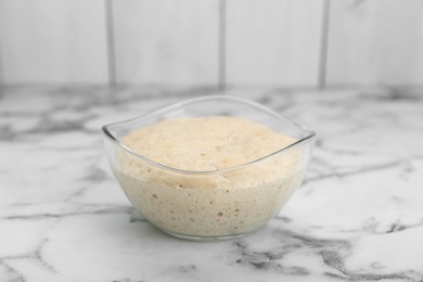 Photo of Leaven in glass bowl on white marble table