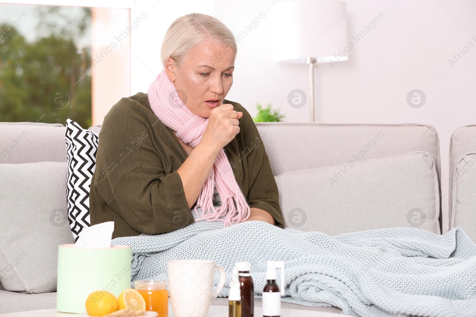 Photo of Ill mature woman suffering from cough on sofa