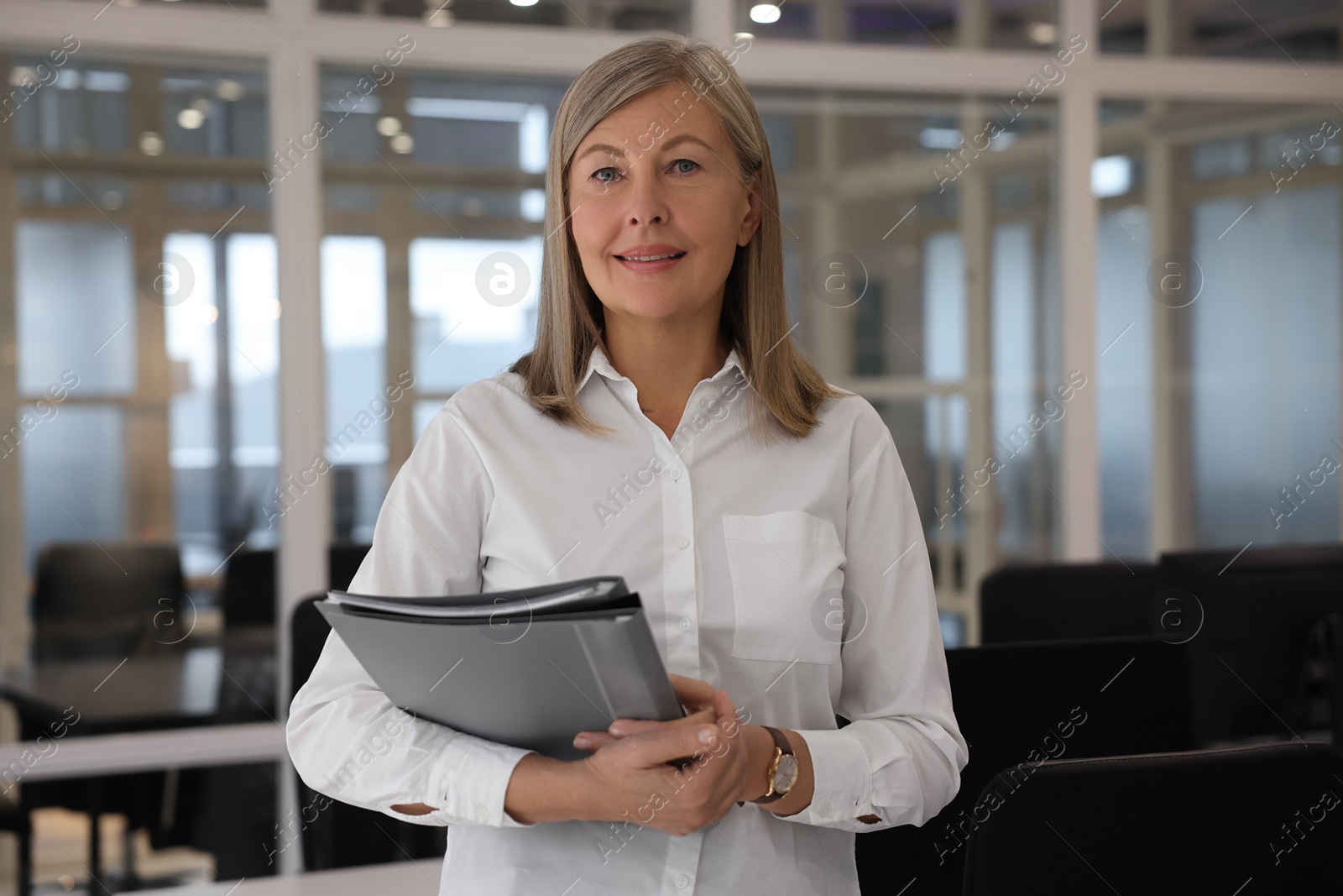 Photo of Smiling woman with folders in office. Lawyer, businesswoman, accountant or manager