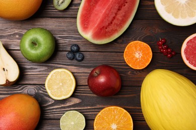 Photo of Different ripe fruits and berries on wooden table, flat lay