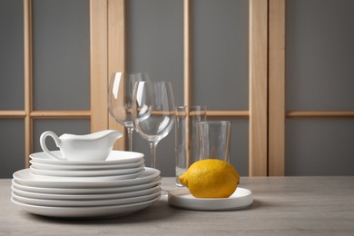 Photo of Set of clean dishware, glasses and lemon on wooden table