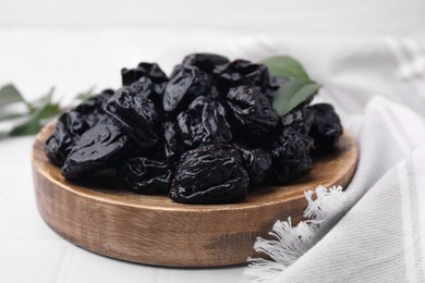 Photo of Sweet dried prunes on white table, closeup