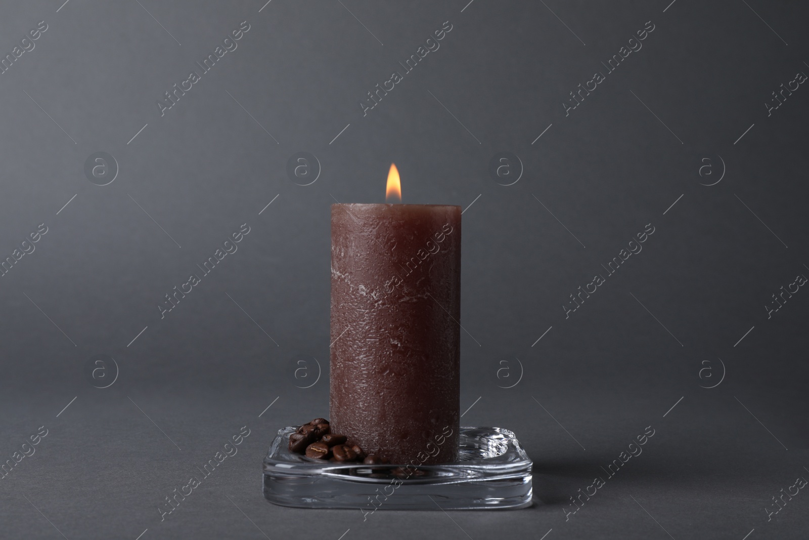 Photo of Burning candle with coffee beans on grey background