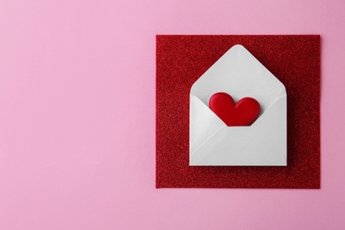 Photo of Composition with white envelope and red wooden heart on pink background, top view. Space for text