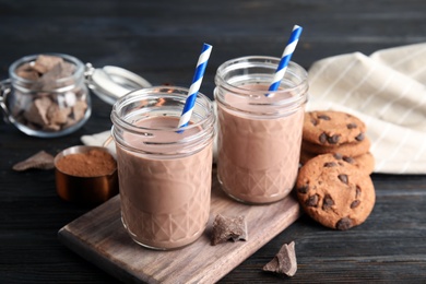 Jars with tasty chocolate milk on wooden table. Dairy drink