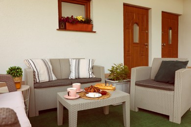 Photo of Outdoor breakfast with tea and croissants on rattan table on terrace
