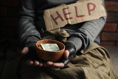 Photo of Poor homeless man with help sign holding bowl of donations, closeup