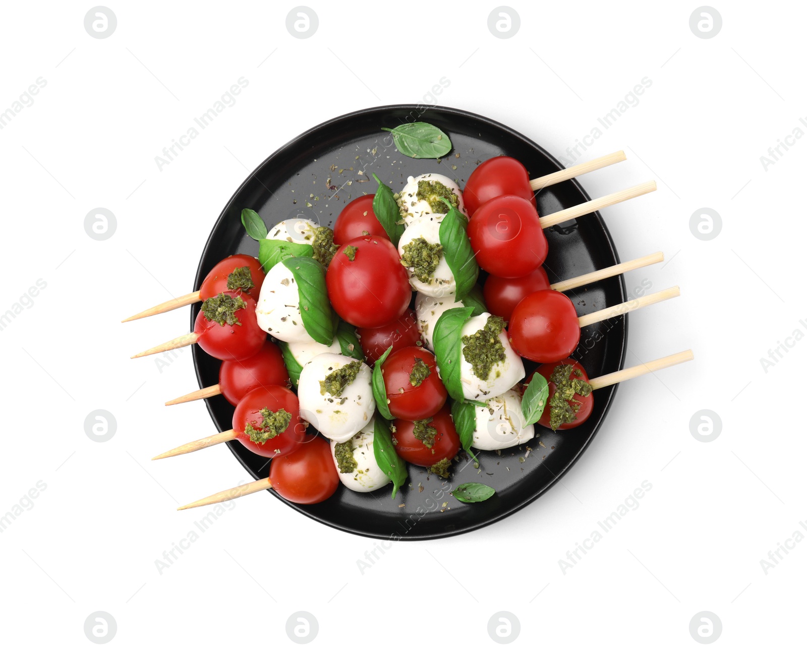 Photo of Plate of Caprese skewers with tomatoes, mozzarella balls, basil and pesto sauce isolated on white, top view