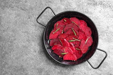 Photo of Slices of raw beetroot in wok pan on grey table, top view