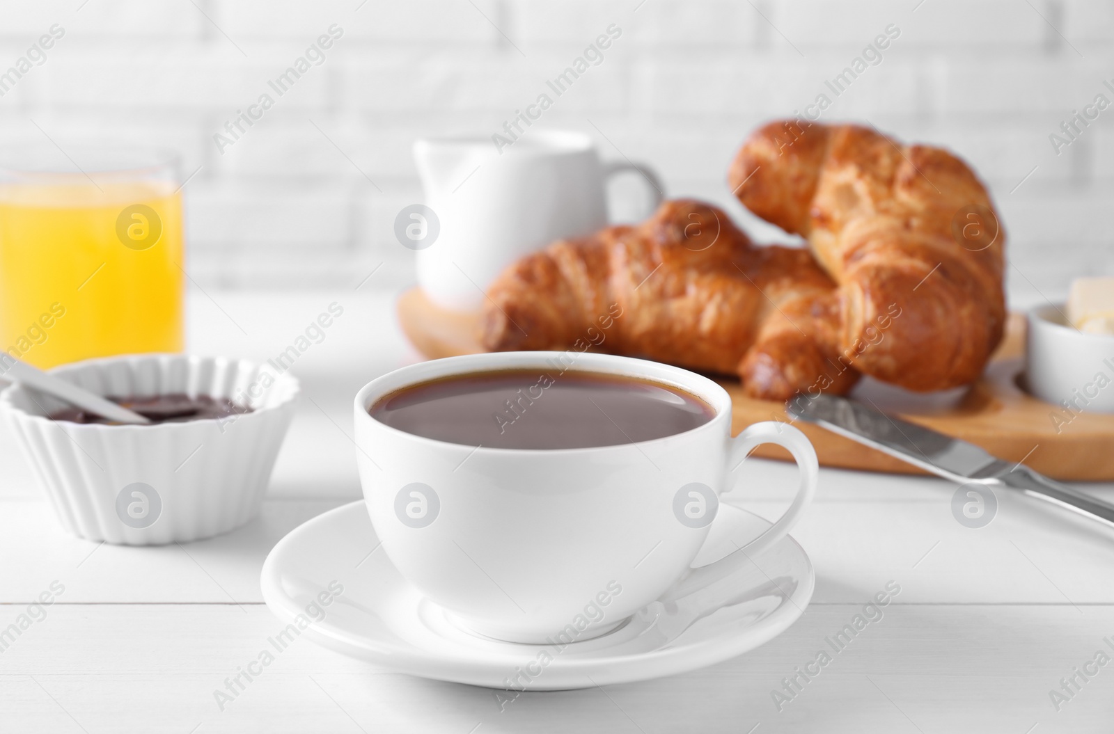 Photo of Fresh croissants, jam and coffee on white wooden table. Tasty breakfast