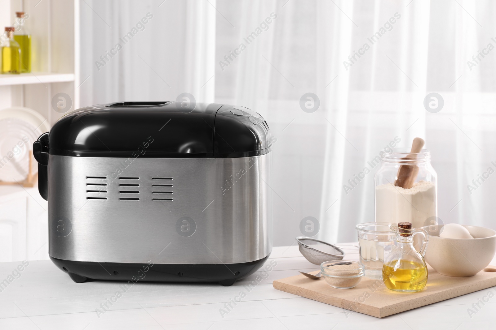 Photo of Breadmaker and different products on white wooden table indoors