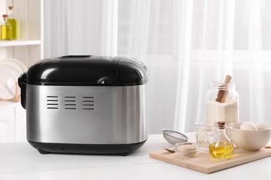 Photo of Breadmaker and different products on white wooden table indoors