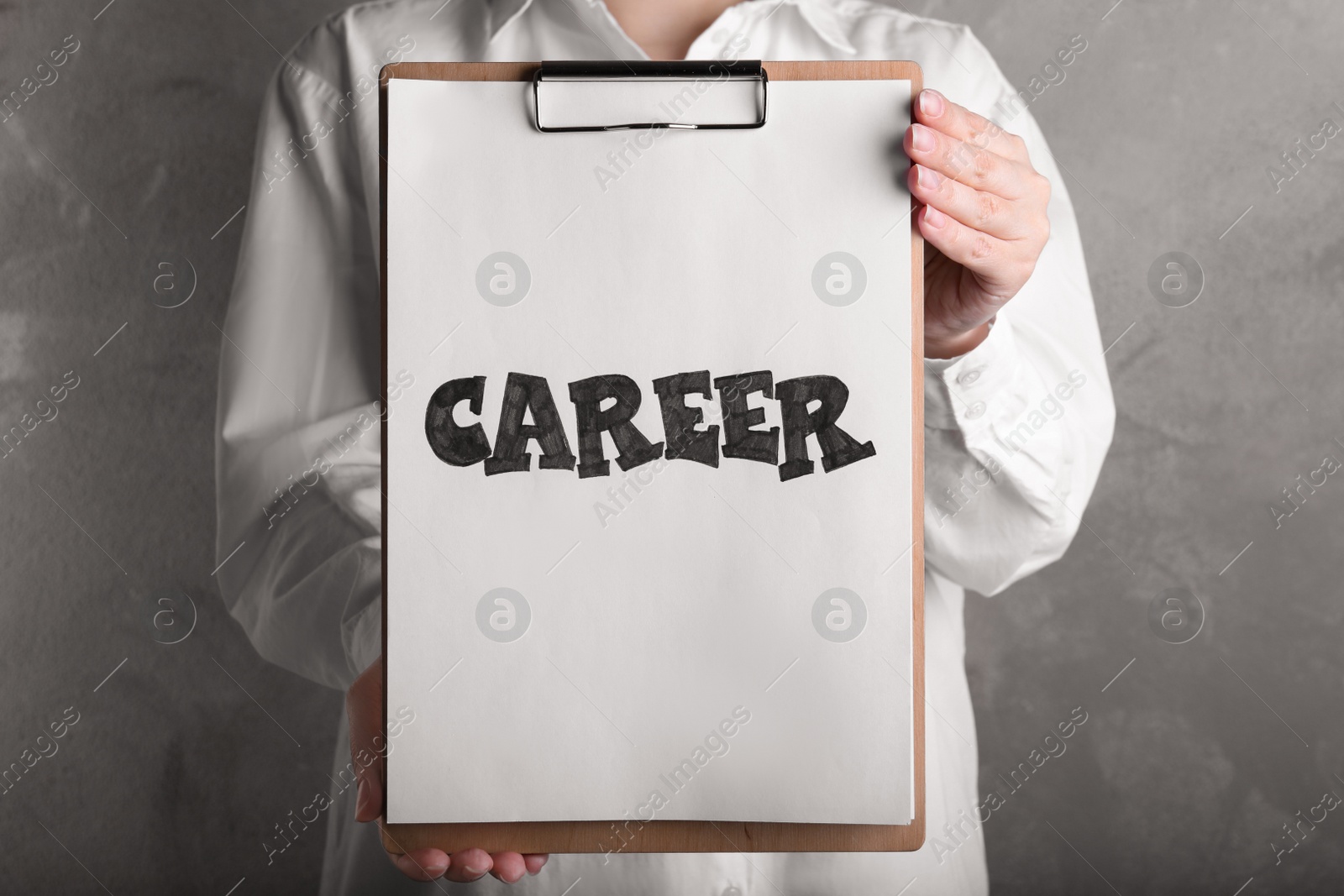 Photo of Woman holding clipboard with word CAREER on beige background, closeup