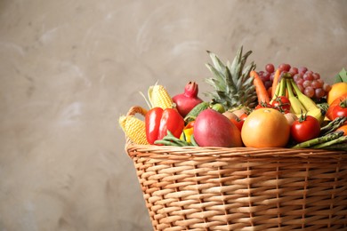 Assortment of fresh organic fruits and vegetables in basket on grey background, closeup. Space for text