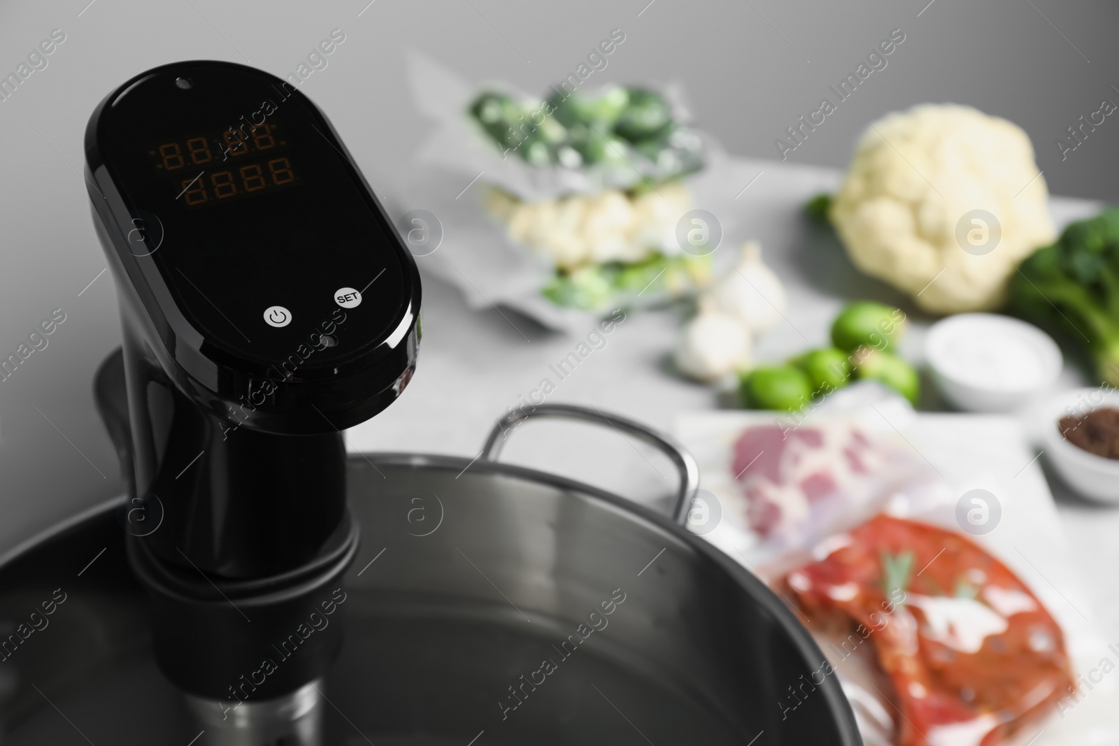 Photo of Sous vide cooker in pot and ingredients on table, closeup. Thermal immersion circulator