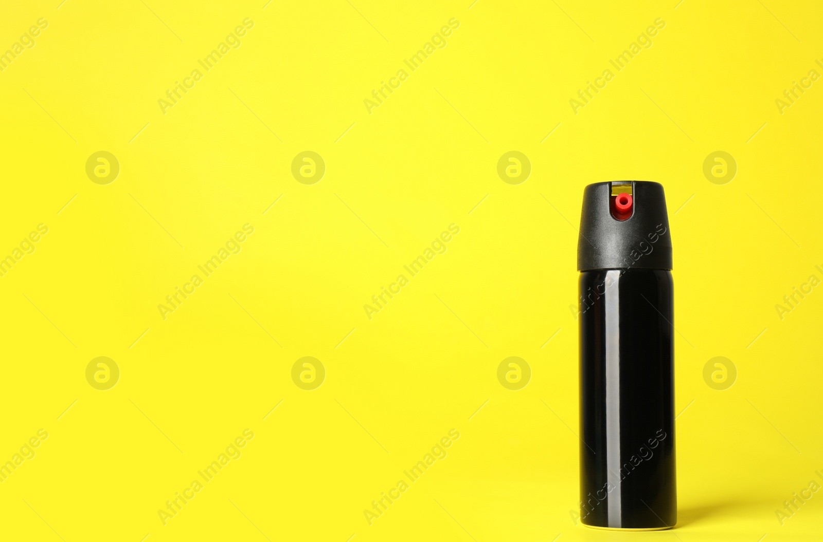 Photo of Bottle of gas pepper spray on yellow background. Space for text