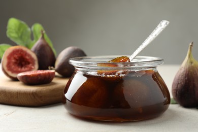 Jar of tasty sweet jam and fresh figs on white table