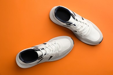 Pair of stylish sports shoes on orange background, flat lay