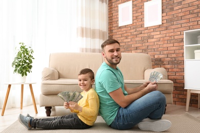 Happy father and son with money at home