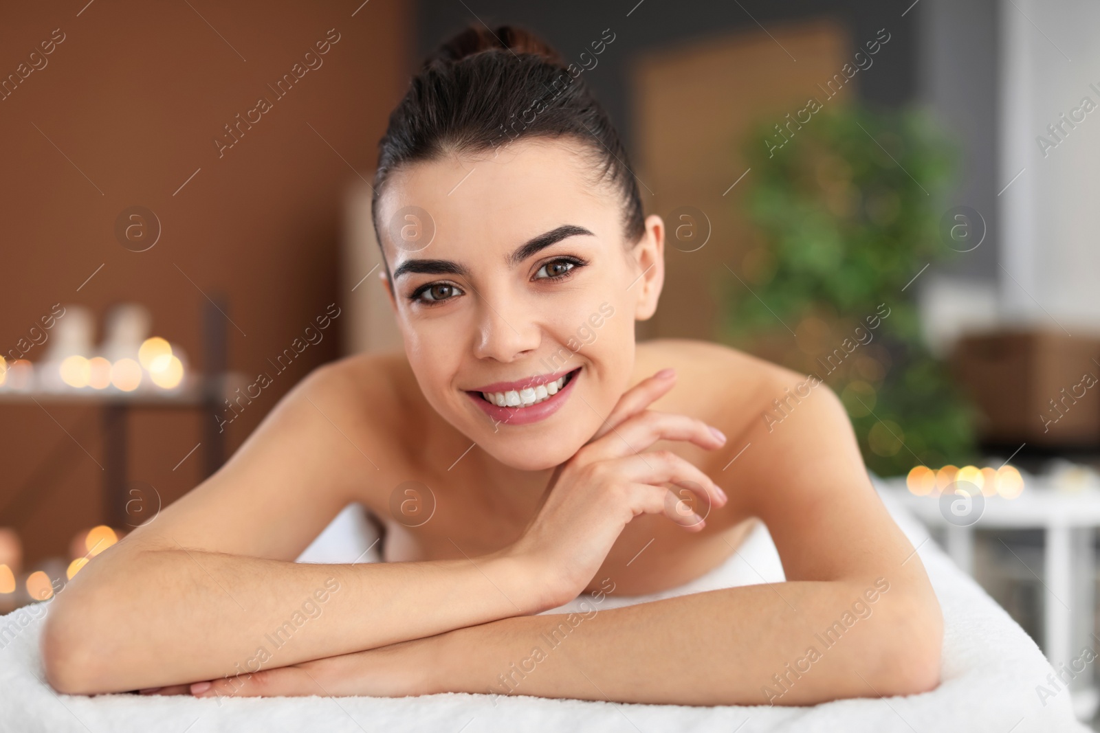 Photo of Young woman lying on massage table in spa salon