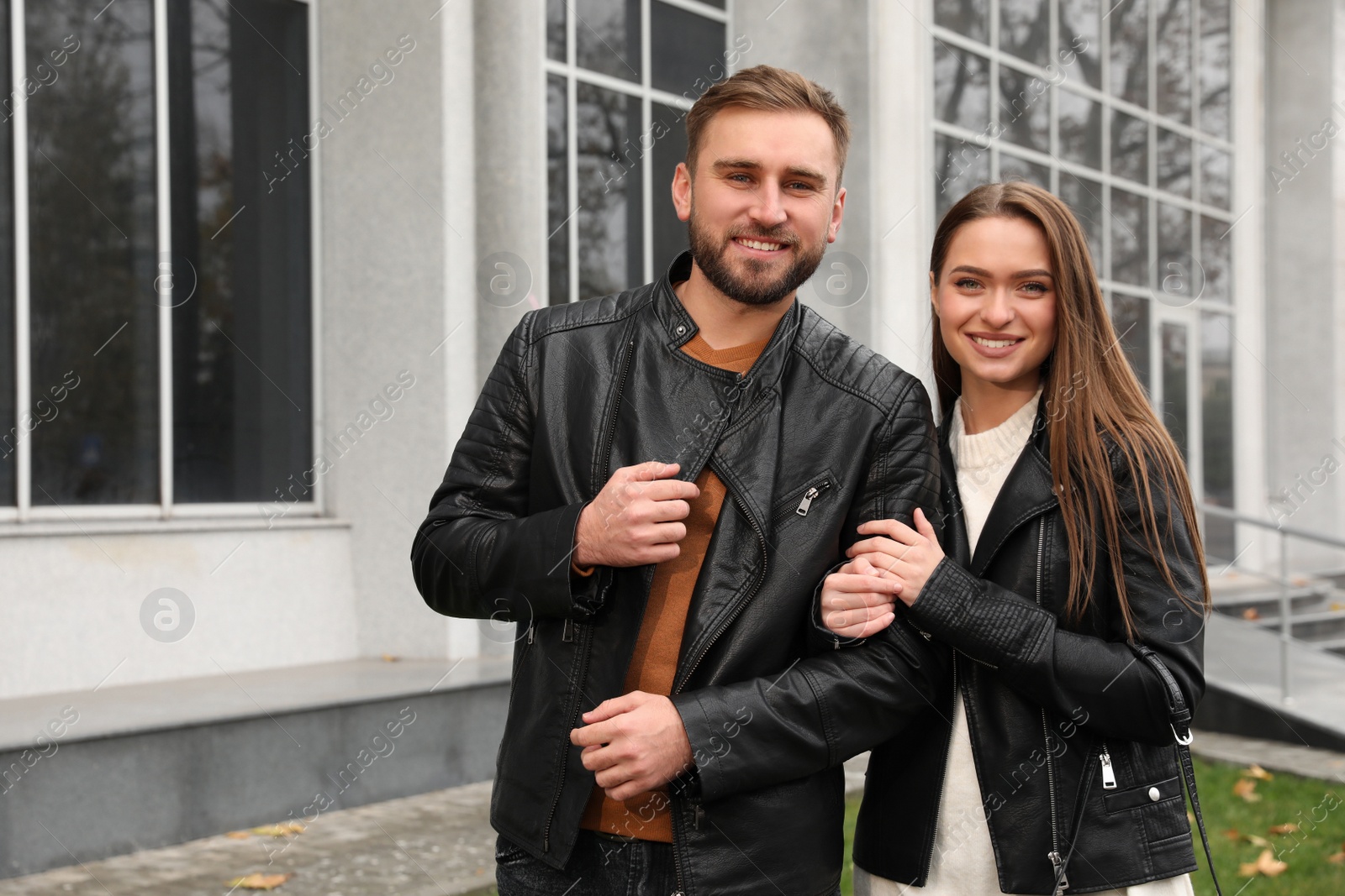 Photo of Happy couple wearing stylish leather jackets on city street. Autumn walk
