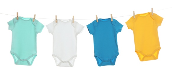 Photo of Colorful baby onesies hanging on clothes line against white background. Laundry day