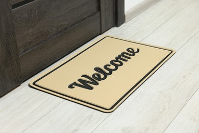 Photo of Beige doormat with word Welcome on white floor near entrance