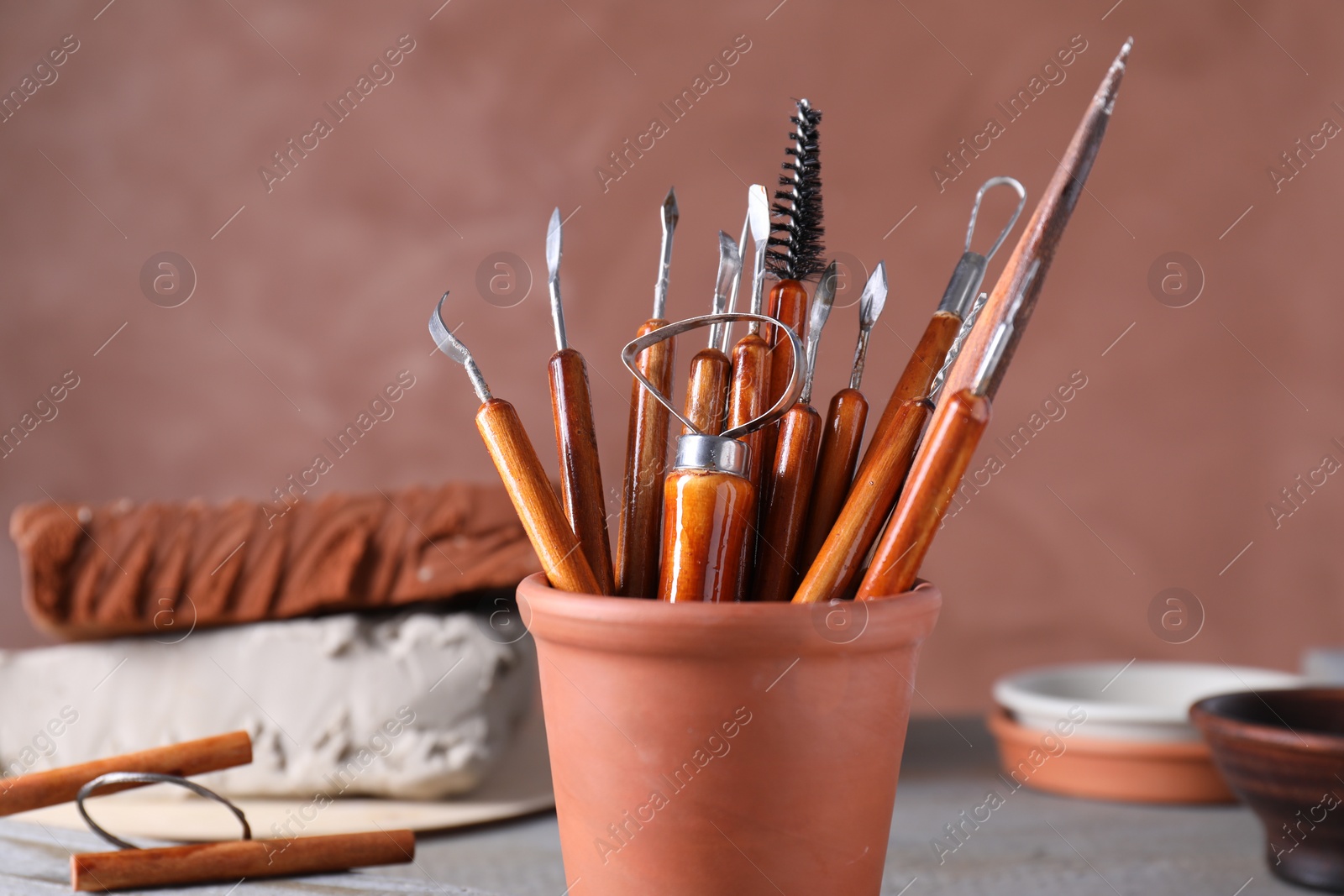 Photo of Clay and set of crafting tools on grey table in workshop, closeup
