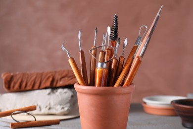 Clay and set of crafting tools on grey table in workshop, closeup